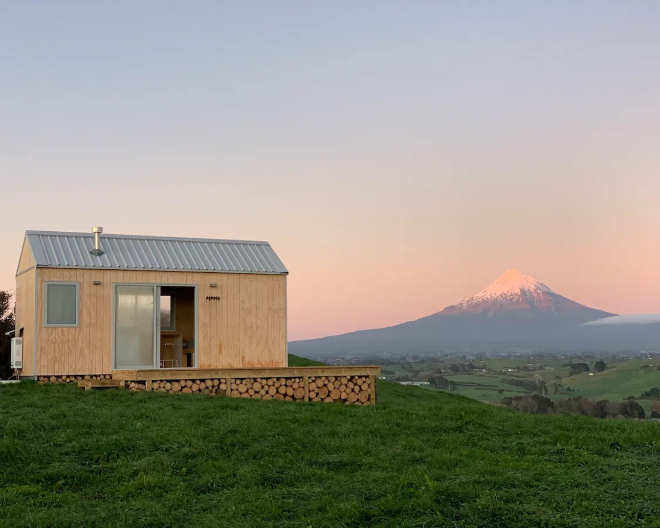 Embodying tranquility, the Repose x Lepperton Farm Stay cabin sits on a lush green hill facing Mount Taranaki