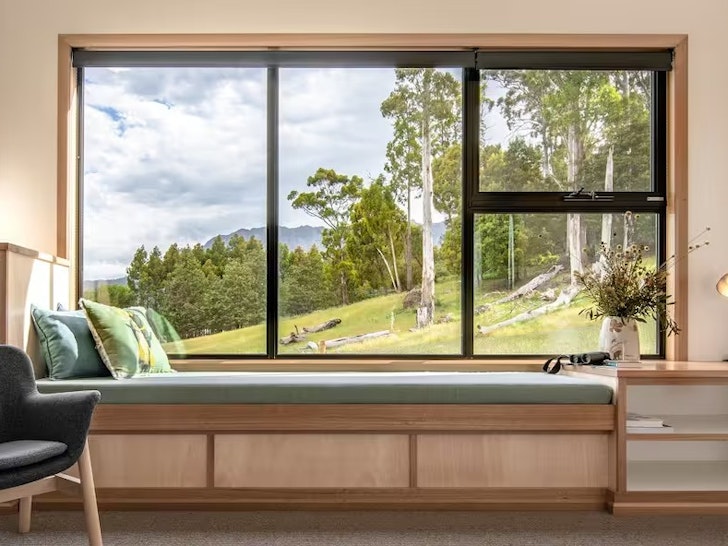 A window seat looks out onto a lush green farm