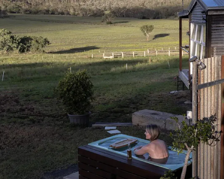 A woman lies in the outdoor bath at Boundary Rider Cabin Airbnb near Brisbane Queensland
