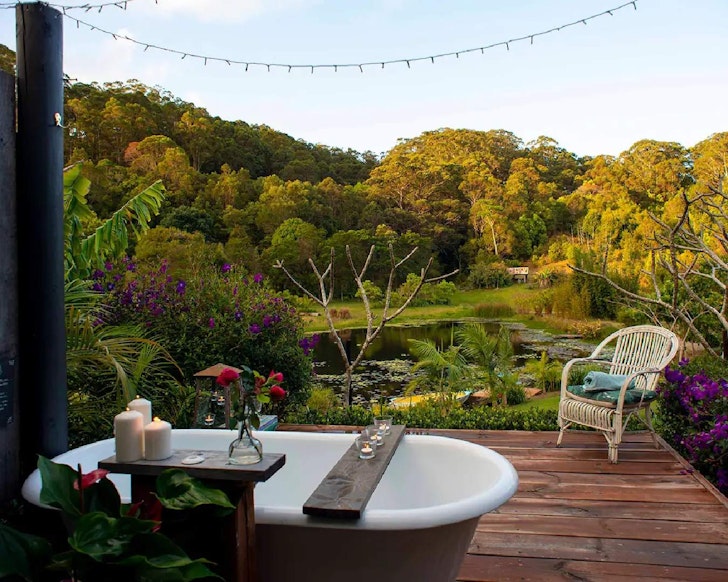 A pretty outdoor bath with a lake in the background at Wildheart Dreamer Cabin Airbnb near Brisbane, Queensland