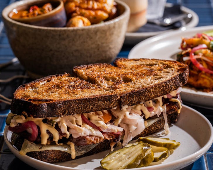 a massive breakfast sandwich with pickles and sourdough bread