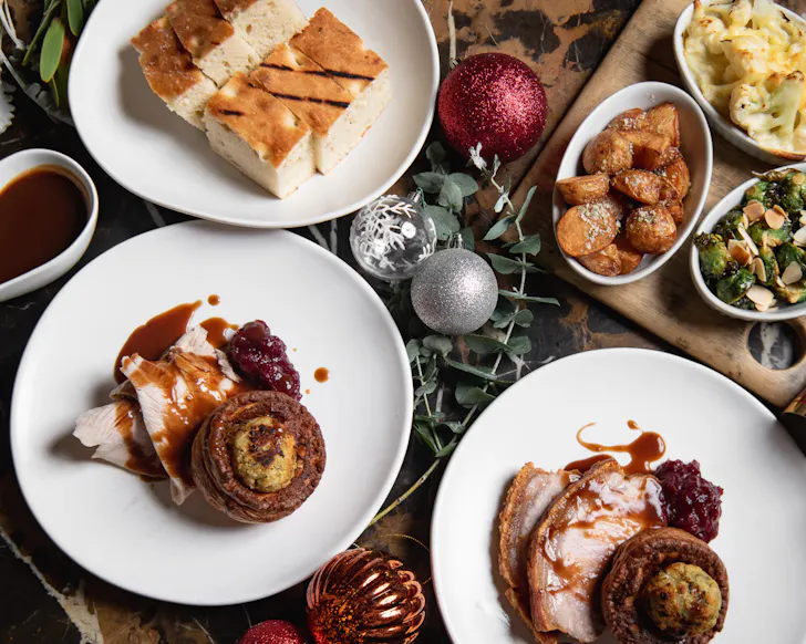 Christmas roast with turkey, gravy, potatoes, cauliflower gratin and festive sides served with Christmas decorations.