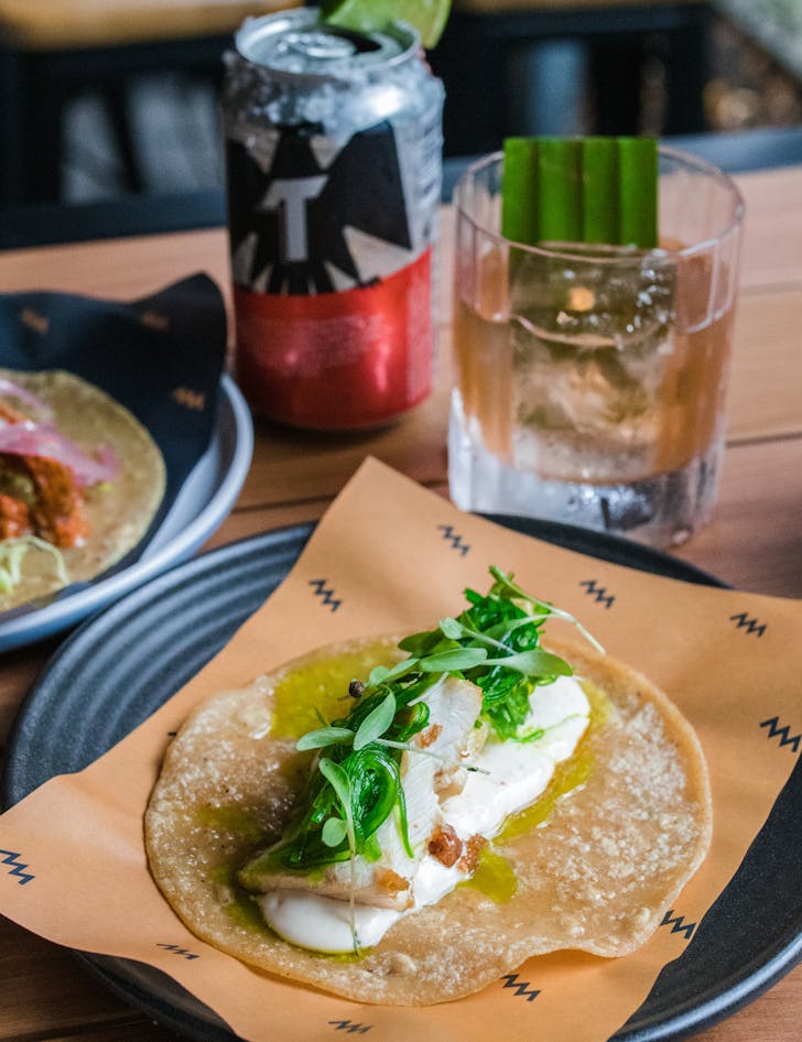 a taco with a beer and a cocktail behind