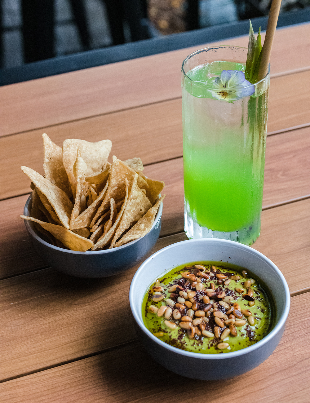 chips, a bowl of guac and a green cocktail