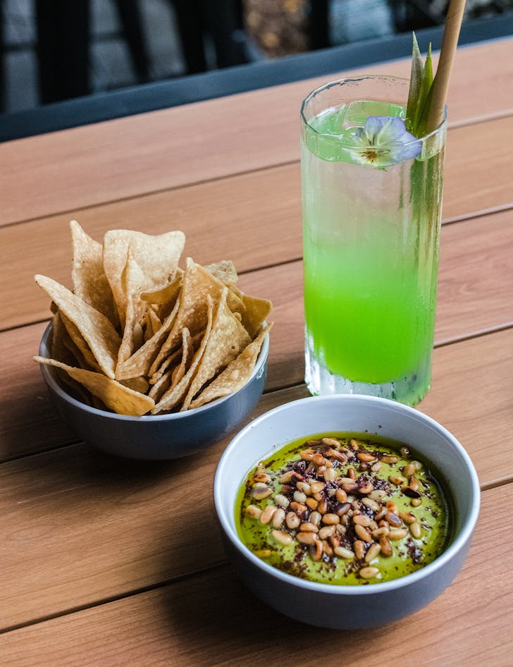 chips, a bowl of guac and a green cocktail