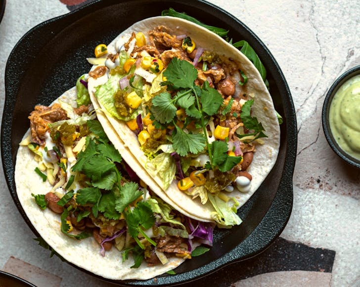 Two pulled pork tacos from Riverside Market's El Rancho are served with a size of zesty sauce