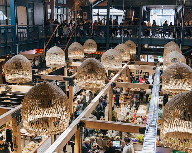 A upper floor view of the indoor Riverside Marketsâmany hanging lights are covered by rope shades.