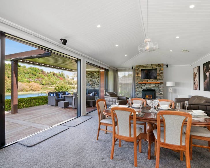 A loung opening out onto a covered wooden deck area backing onto a river.