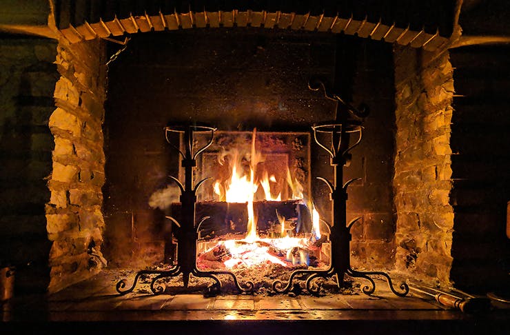 A cosy looking hearth with a roaring fire.