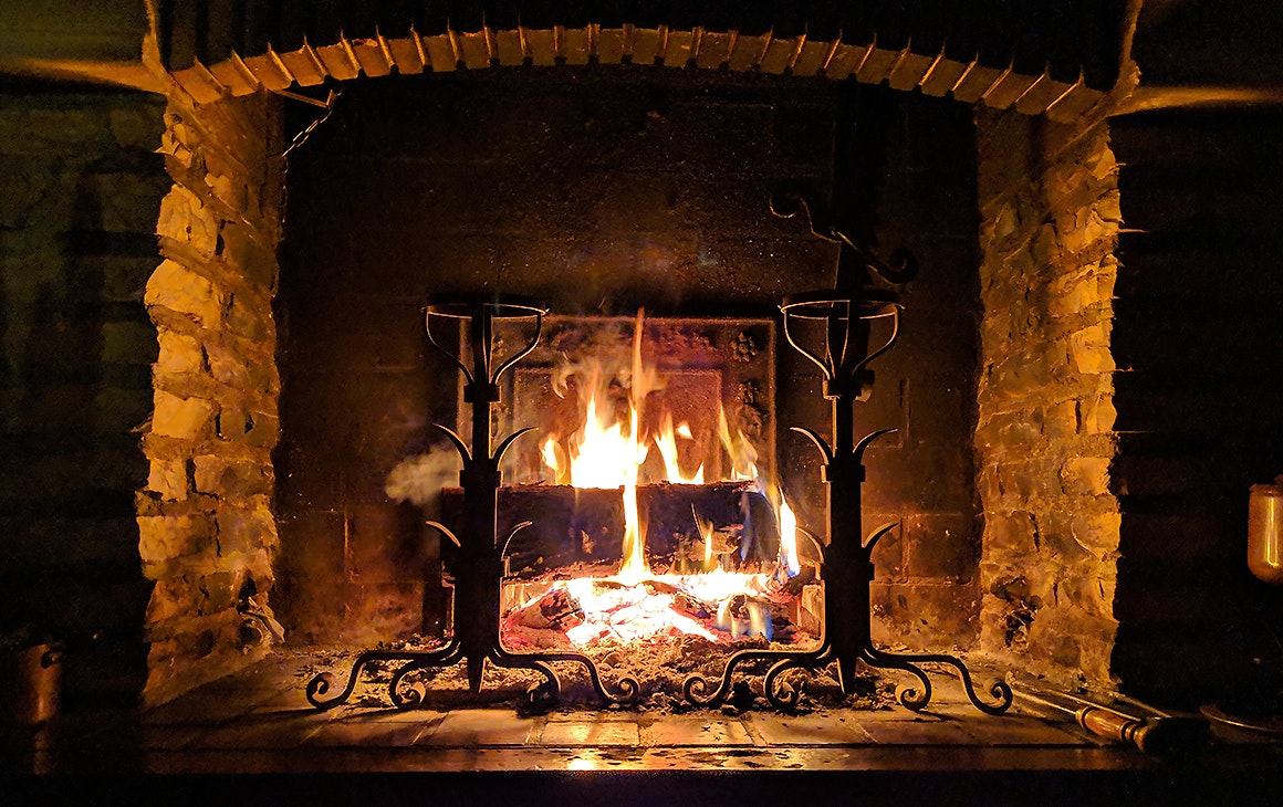 A cosy looking hearth with a roaring fire.