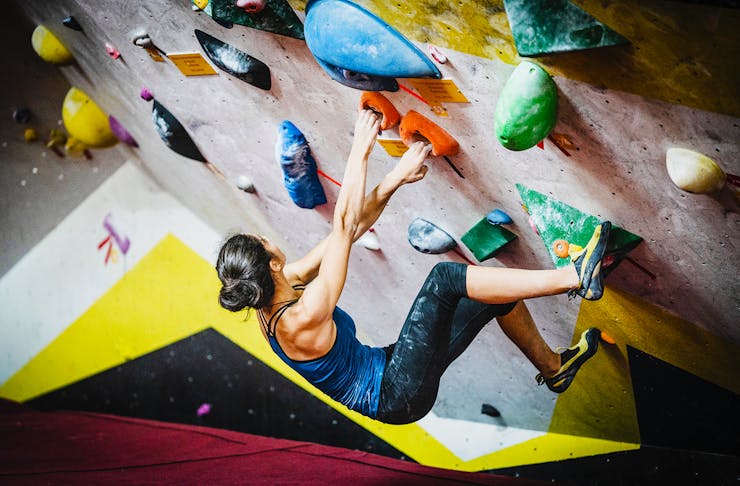 A girl scales a rock climbing wall with aplomb.