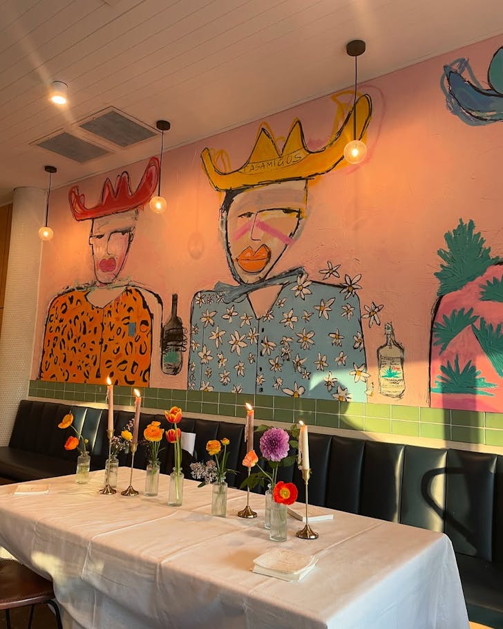 A pink mural on the wall of Rocker Bondi, above a table filled with fresh flowers