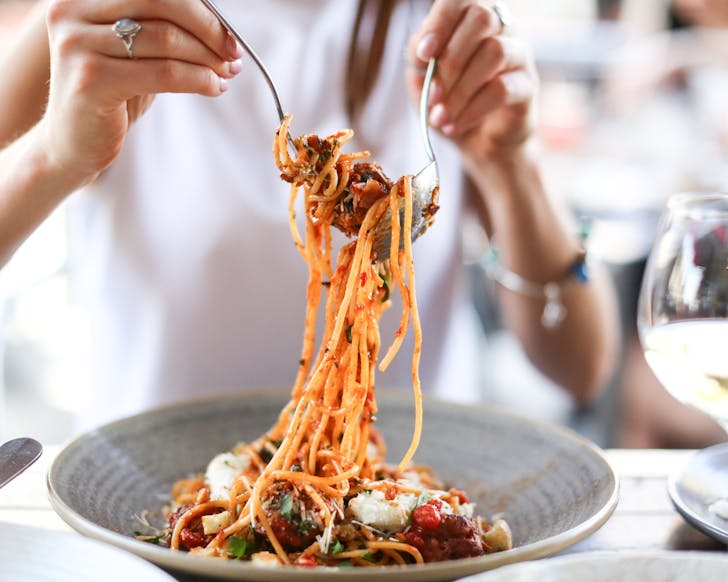 a woman twirls spaghetti around a fork