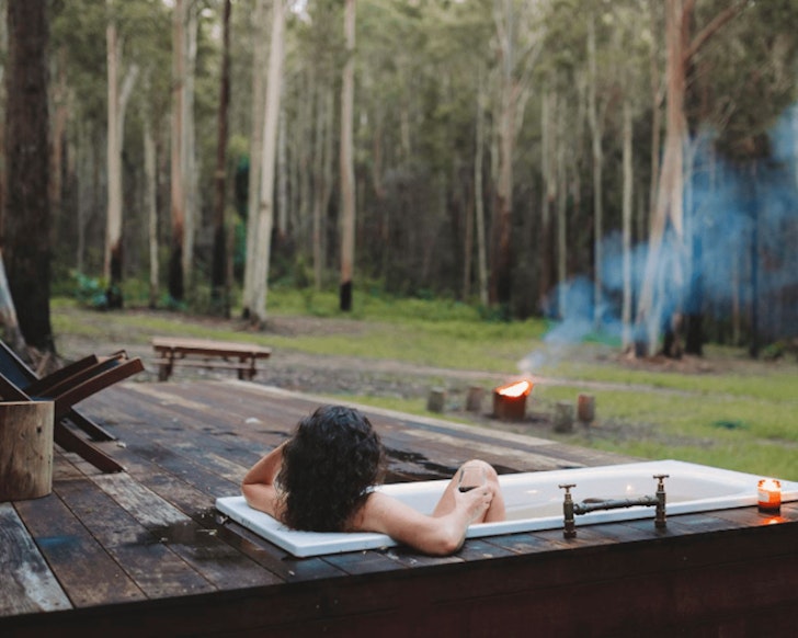 A guest soaks in the outdoor bath at Soul Wood Airbnb one of the best romantic getaways in Australia