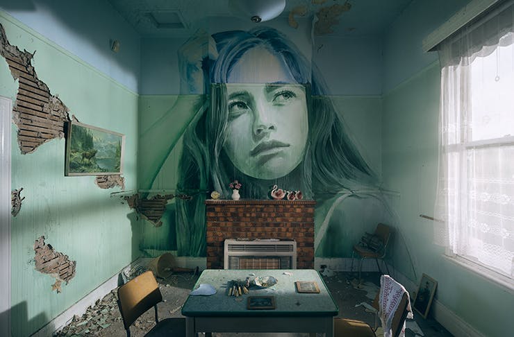 A detailed painting of a woman on a wall inside a dilapidated cottage.