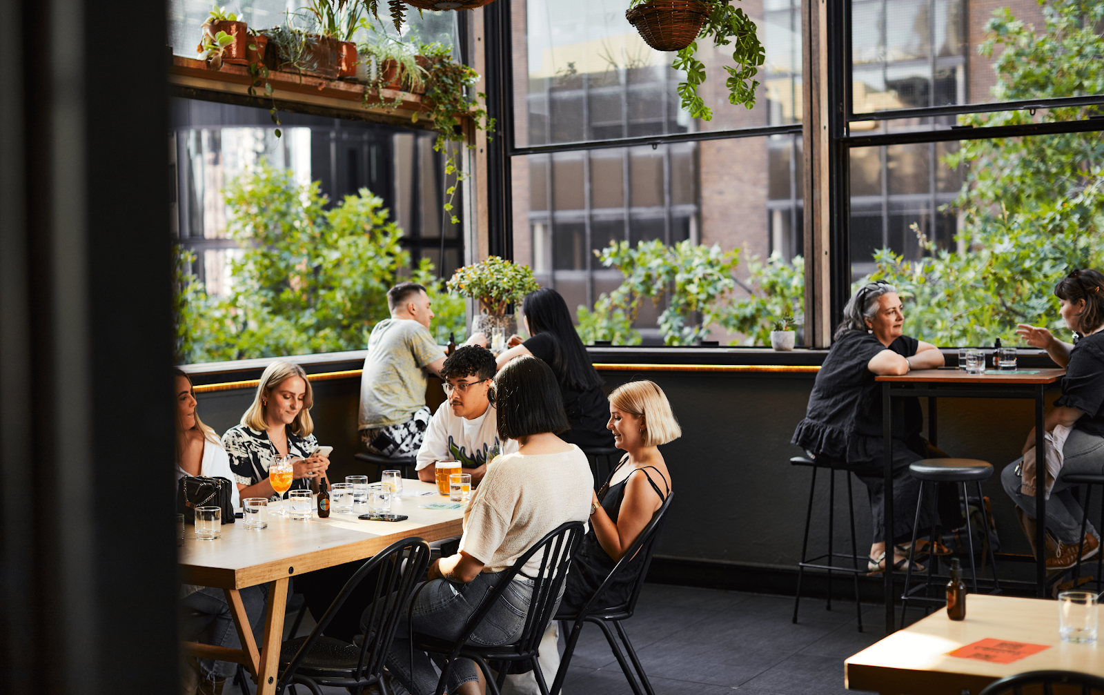 A garden filled open-air venue with people drinking at one of the best rooftop bars in Melbourne.