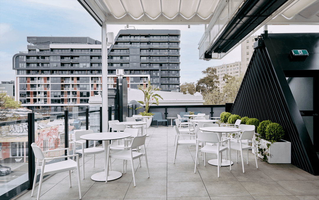 An open-air space with white chairs and blue skies a suitable contender for the best rooftop bar in melbourne