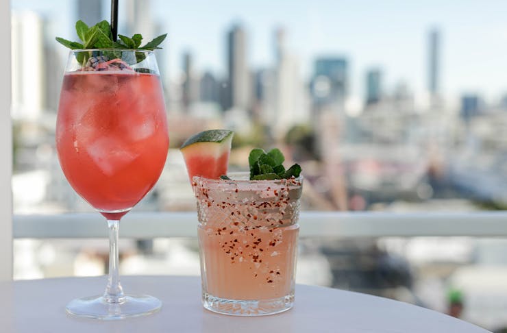 two cocktails in front of a view of a city skyline