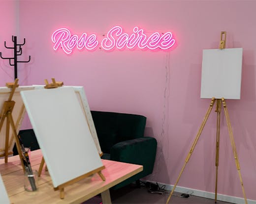 a neon sign in a paint and sip studio