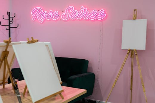 a neon sign in a paint and sip studio
