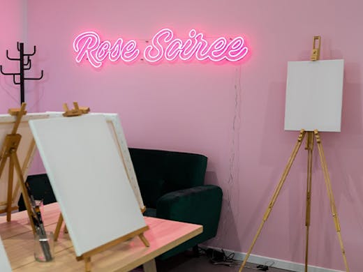 a neon sign in a paint and sip studio
