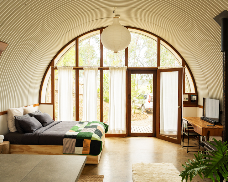 A light filled bedroom with large round windows in a romantic NSW airbnb