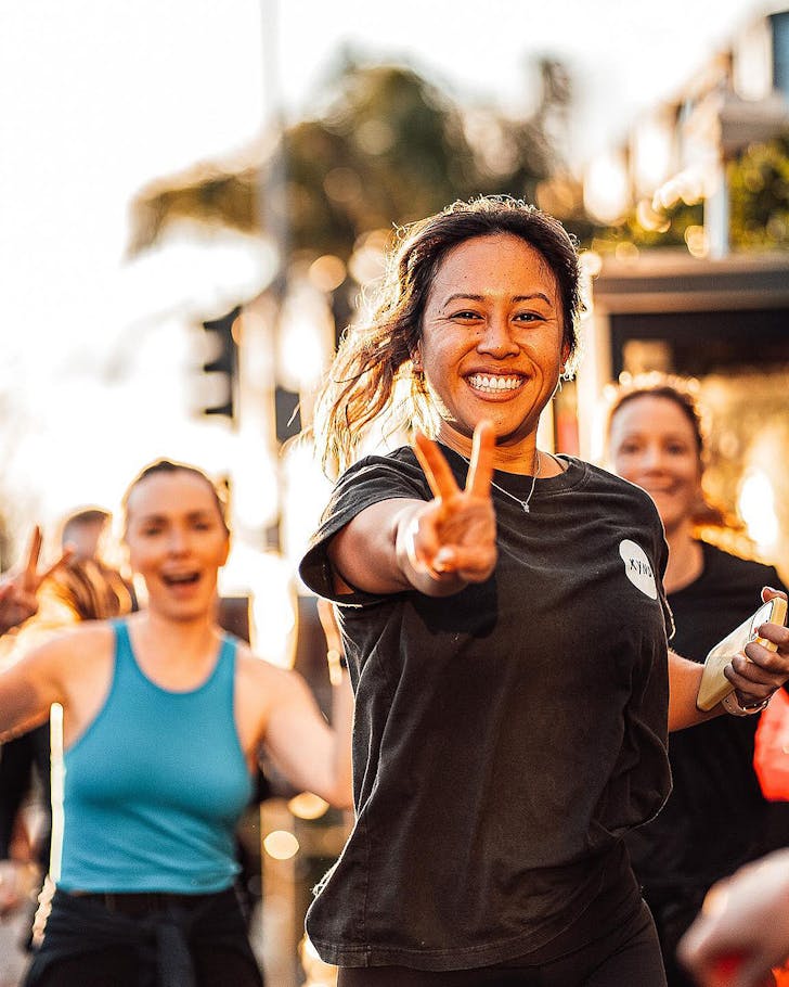 A woman runs and holds up a peace sign at Run4Auckland.