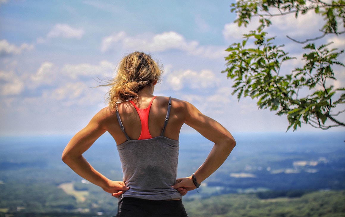 A woman stands looking at the view after a probable sprint uphill
