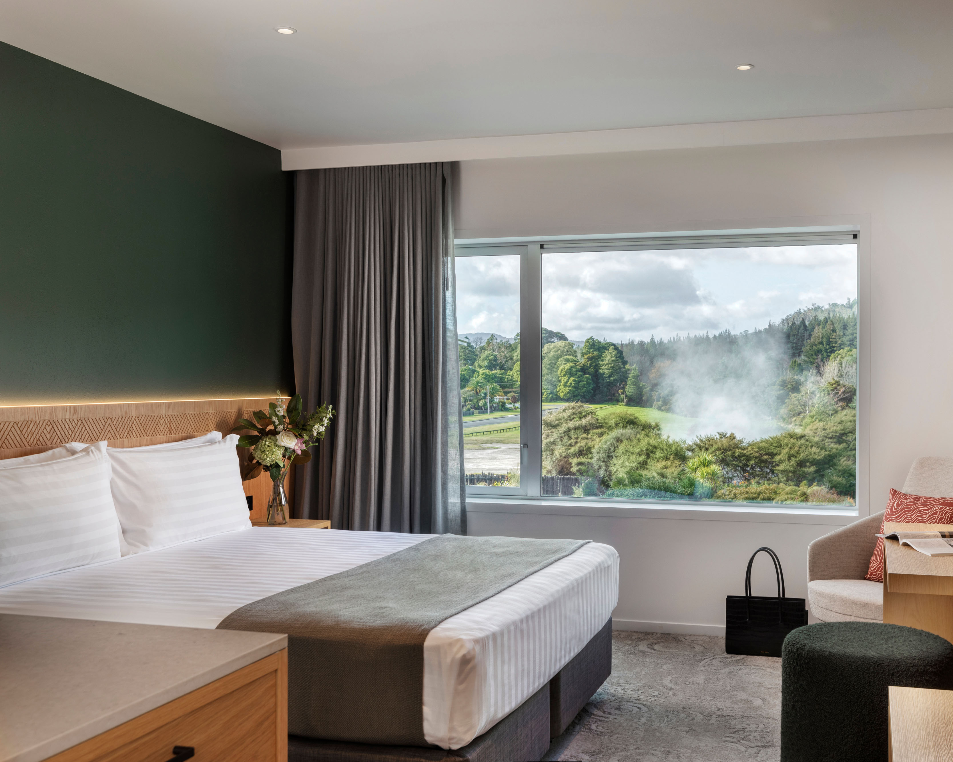Hotel room at Rydges Rotorua, with a queen sized bed, desk and TV with views of the thermal valley out the window.