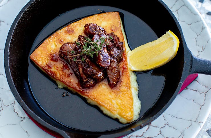 a piece of grilled cheese in a small pan topped with figs