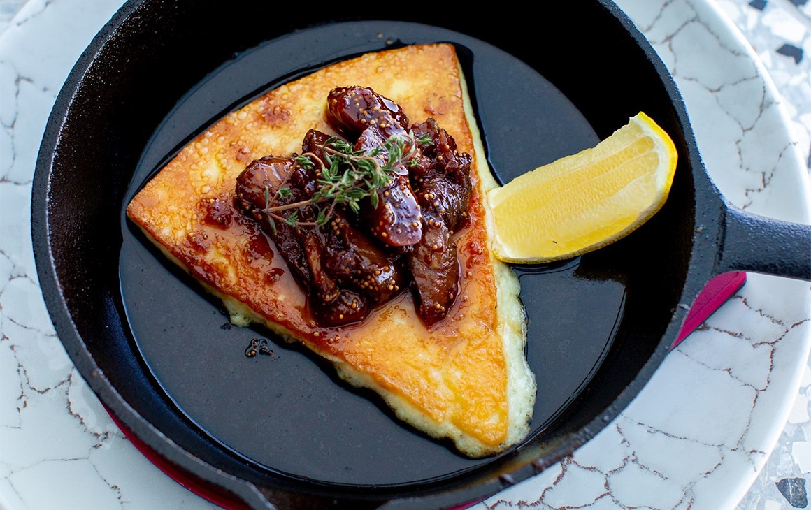 a piece of grilled cheese in a small pan topped with figs