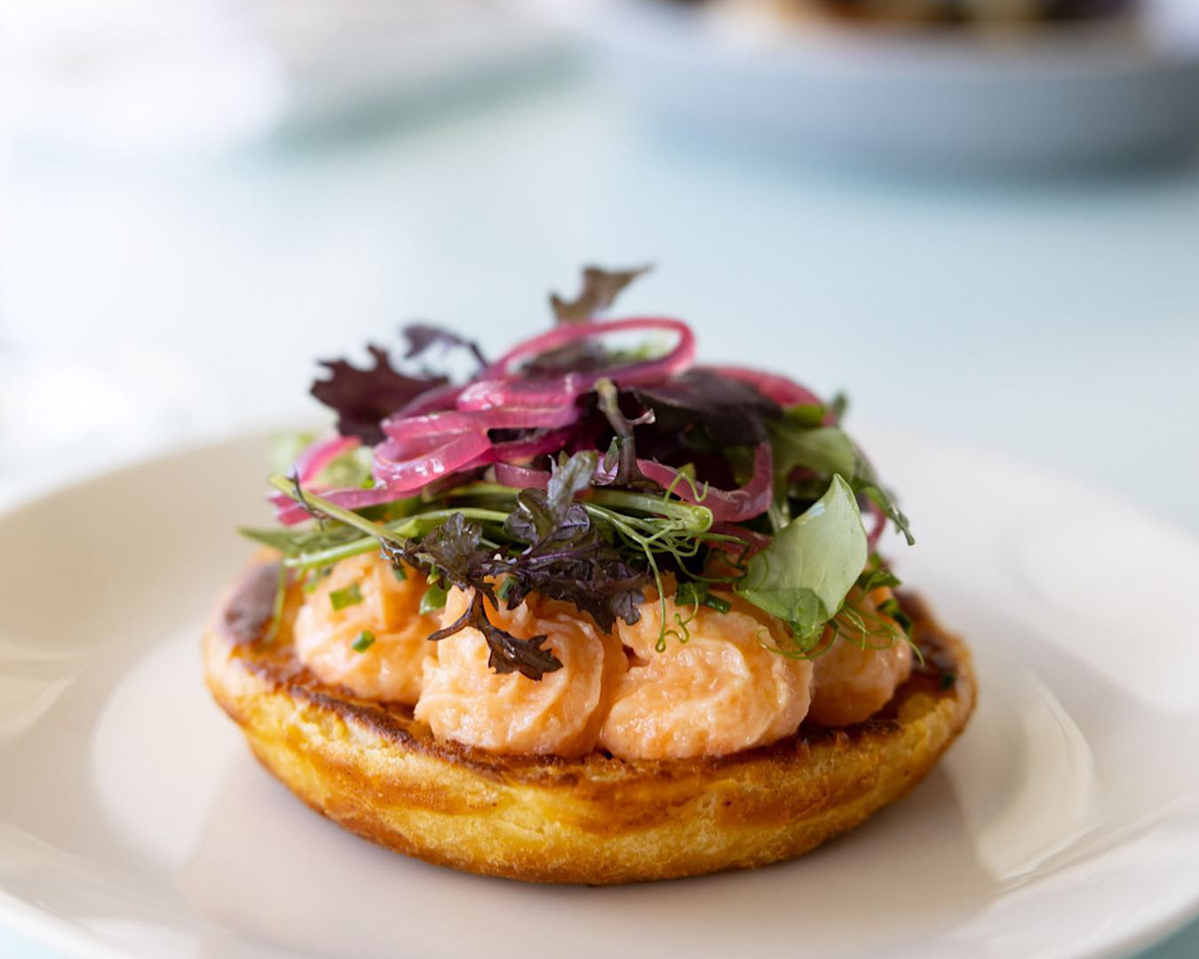 A plump salmon and horseradish crumpet sits on a plate at The Oyster Inn, one of the best restaurants on Waiheke Island. 