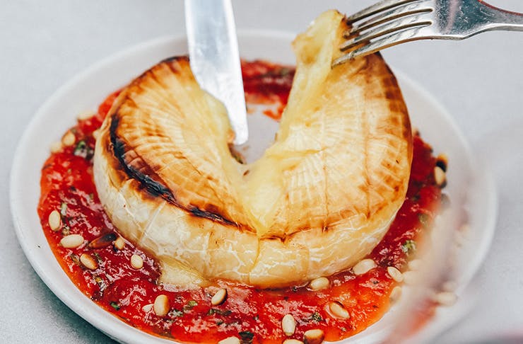 someone slicing into baked brie