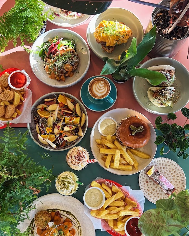 A massive brunch spread pictured from a birds eye angle on a pink and green table.