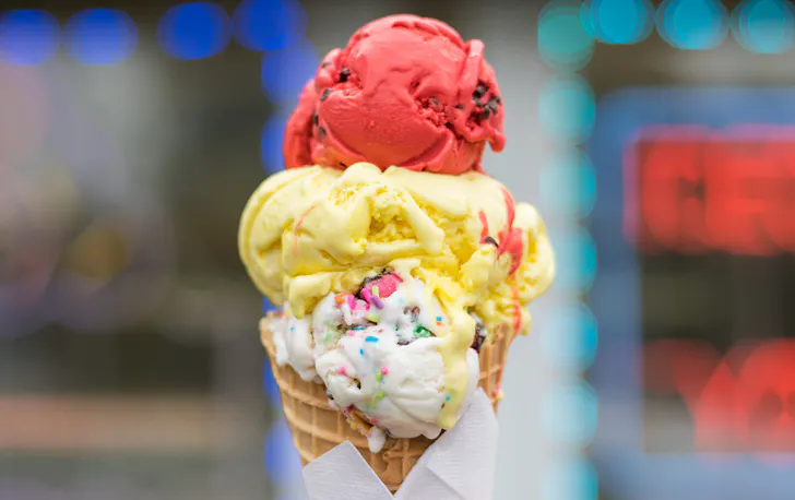 three scoops of ice cream stacked on a waffle cone
