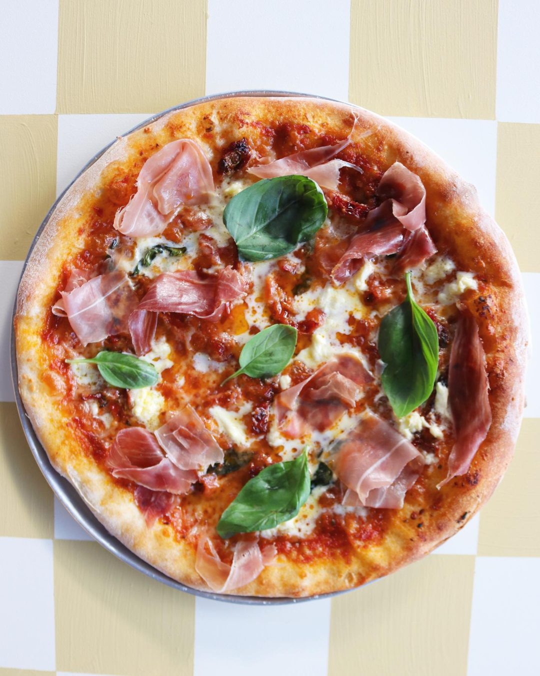 A basil, prosciutto, and straccitella-topped pizza looks enticing at Scopa