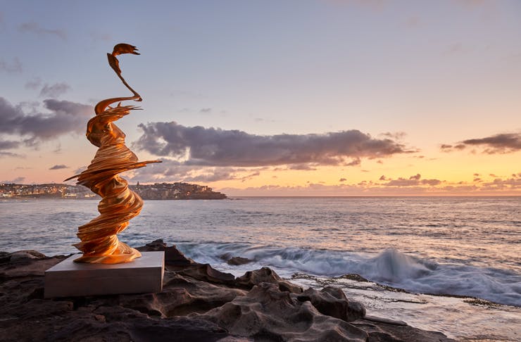 A sculpture on the cliffs at Bondi Beach at sunrise