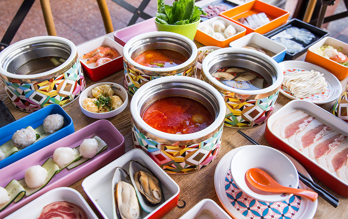 hot pots on a table surrounded by plates of food