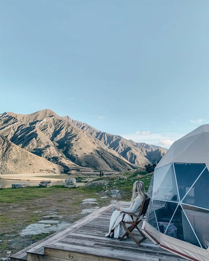 Someone gazes at the view outside a geodesic dome.