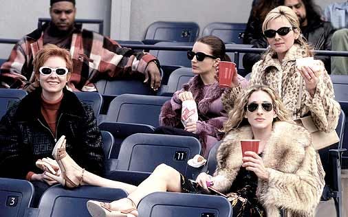 four women sitting on seats with big jackets and glasses