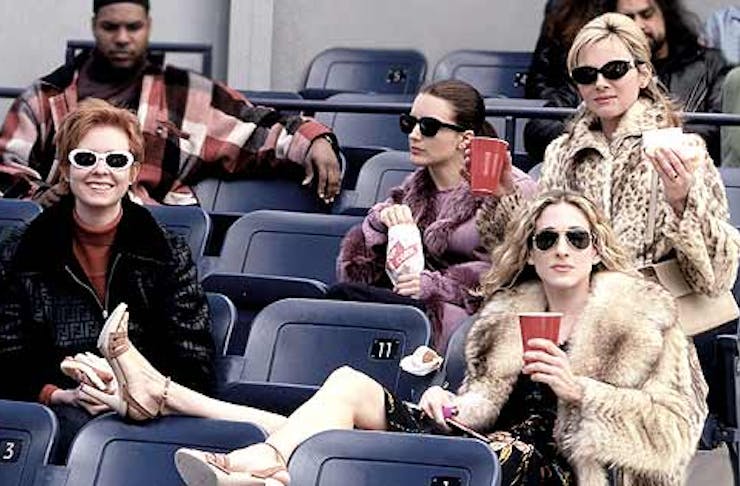 four women sitting on seats with big jackets and glasses