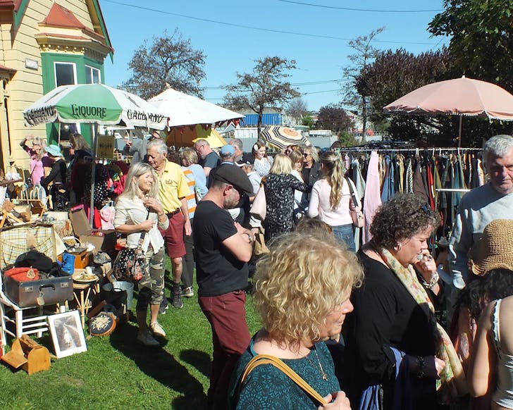 People peruse the Shabby Chic Market Day on a sunny day, crowding the lawn outside the yellow 19th-century Rochester Villa.