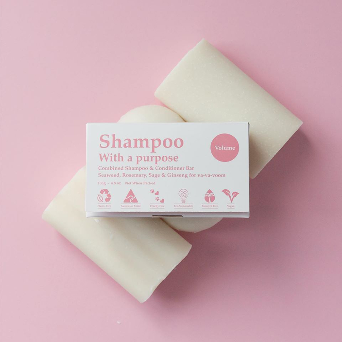 three shampoo bars lined up on a pink background with a box on top.