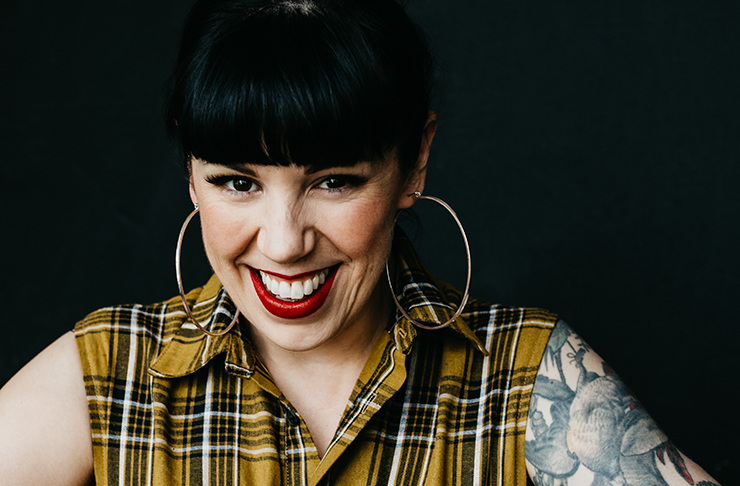 Chef Shannon Martinez smiling into camera in front of a black background.