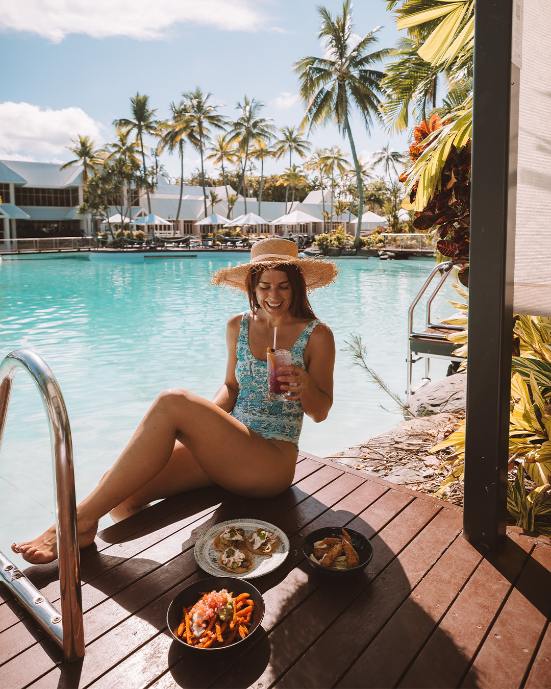 a woman drinking a cocktail by the pool at Sheraton Grand Mirage Port Douglas