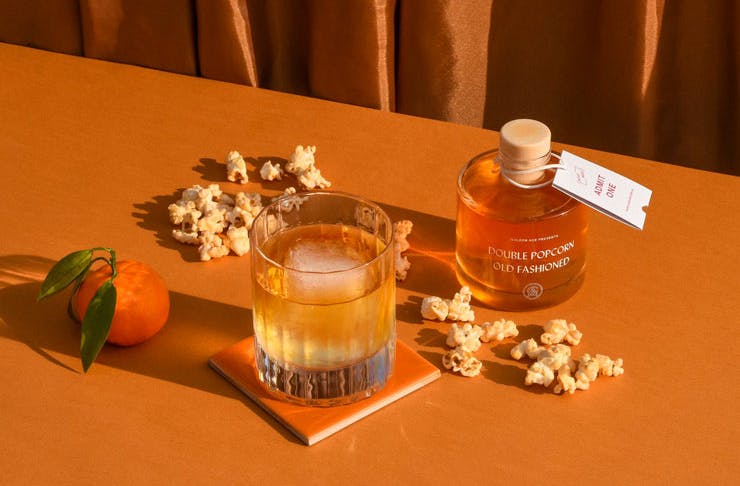 A bottled cocktail displayed with some popcorn. 