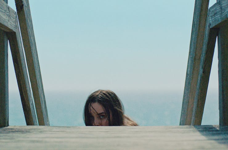 A woman crying, while climbing up wooden stairs from the film The Beach House.