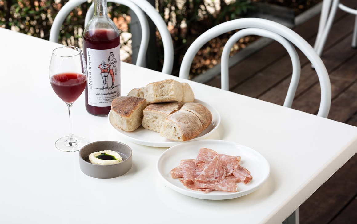 several small plates of snacks and a bottle of wine on a white table
