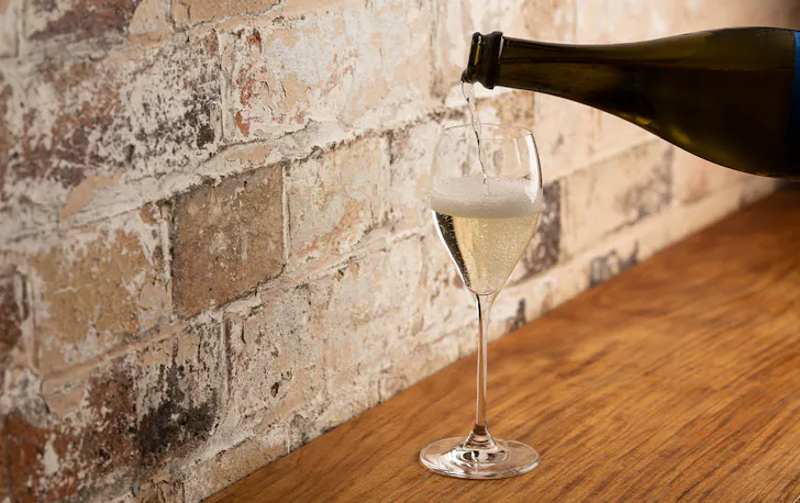 a glass of prosecco being poured