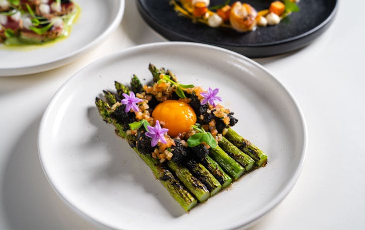 a dish of asparagus with flowers and egg yolk